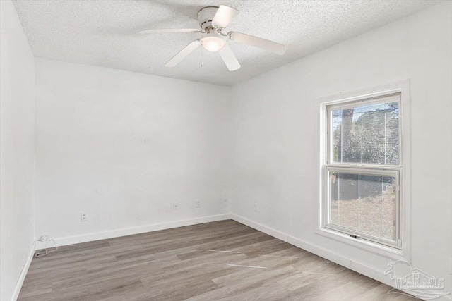 empty room with a textured ceiling, a ceiling fan, baseboards, and wood finished floors