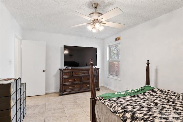 bedroom featuring light tile patterned floors, a ceiling fan, baseboards, and a textured ceiling