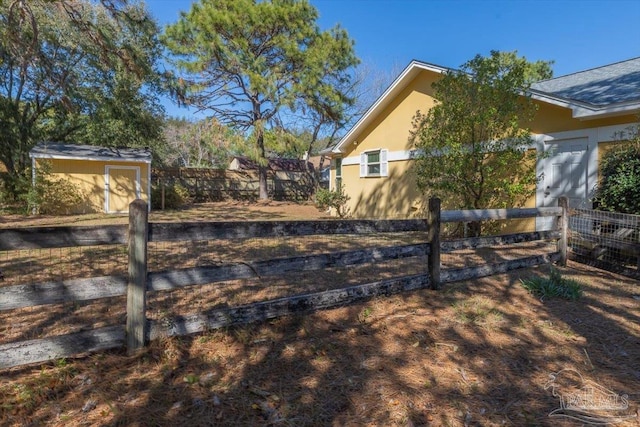 view of yard featuring a storage unit, an outdoor structure, and fence