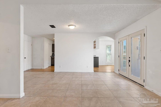 entryway featuring light tile patterned floors, visible vents, arched walkways, french doors, and a textured ceiling