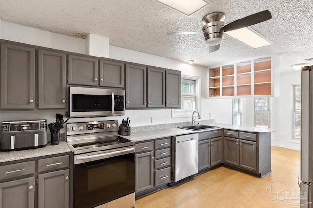 kitchen with a sink, a peninsula, light countertops, and stainless steel appliances