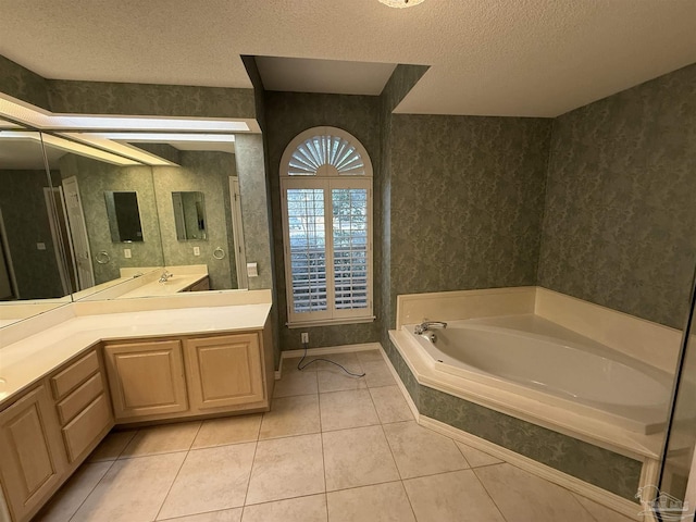 bathroom with tile patterned floors, tiled tub, vanity, and a textured ceiling