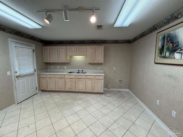 kitchen featuring sink, track lighting, a textured ceiling, light brown cabinetry, and light tile patterned floors