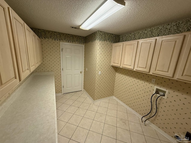 laundry room with light tile patterned floors, cabinets, a textured ceiling, and washer hookup