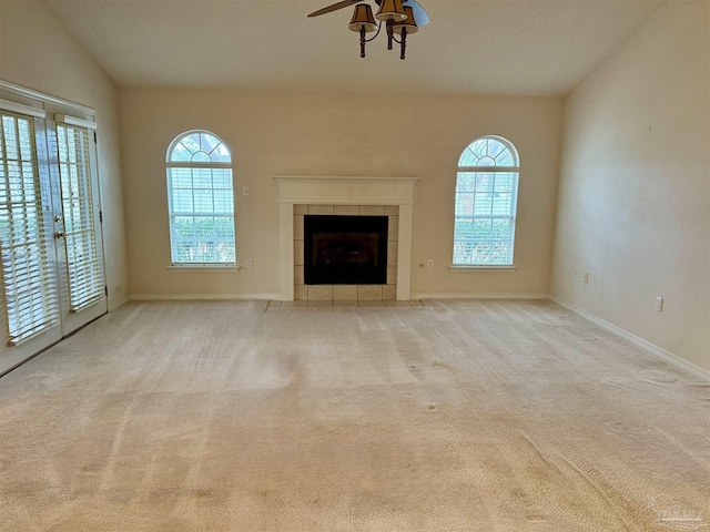 unfurnished living room featuring french doors, vaulted ceiling, ceiling fan, a fireplace, and light colored carpet