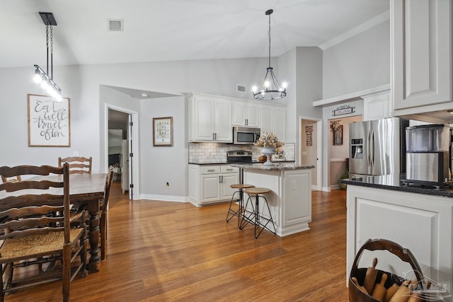 1333 Dubose Rd, Gulf Breeze, FL 32563 - kitchen with appliances with stainless steel finishes, a center island, light wood-type flooring, decorative backsplash, and white cabinetry