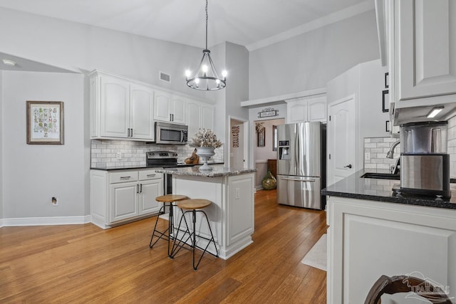 1333 Dubose Rd, Gulf Breeze, FL 32563 - kitchen with appliances with stainless steel finishes, a center island, a kitchen bar, white cabinetry, and tasteful backsplash