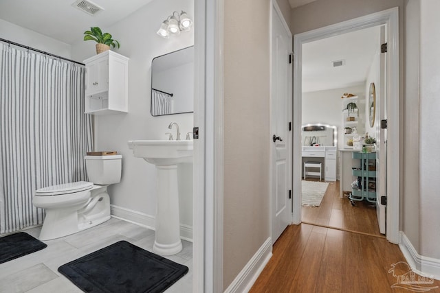 1333 Dubose Rd, Gulf Breeze, FL 32563 - bathroom featuring wood finished floors, toilet, baseboards, and a shower with shower curtain