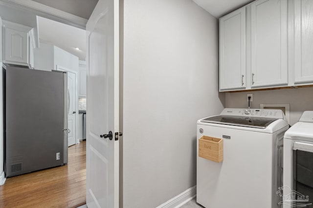 1333 Dubose Rd, Gulf Breeze, FL 32563 - clothes washing area with cabinet space, washing machine and clothes dryer, light wood-style floors, and baseboards