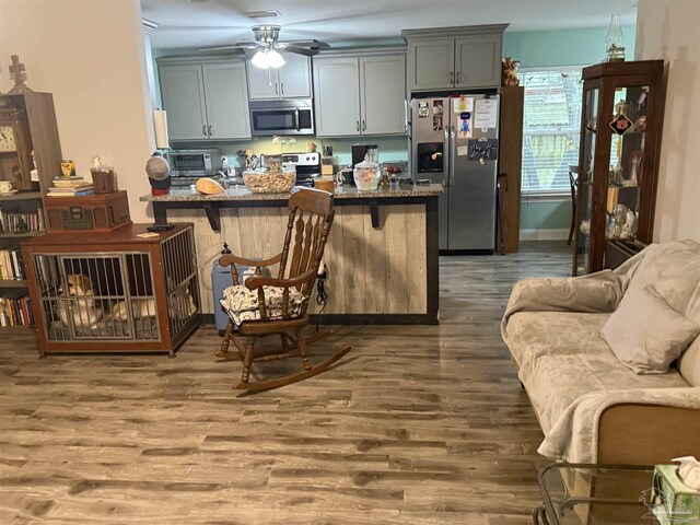 5407 Maverick Ln, Gulf Breeze, FL 32563 - kitchen with stone counters, a breakfast bar area, ceiling fan, appliances with stainless steel finishes, and wood finished floors