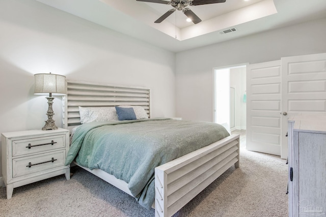 carpeted bedroom with a tray ceiling and ceiling fan