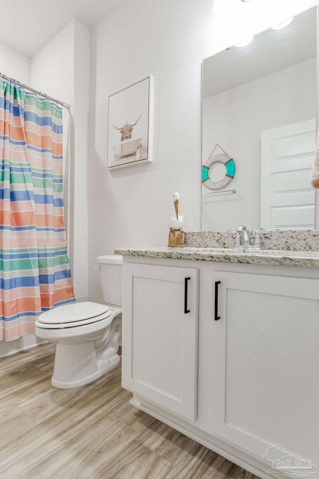 bathroom featuring curtained shower, hardwood / wood-style floors, vanity, and toilet