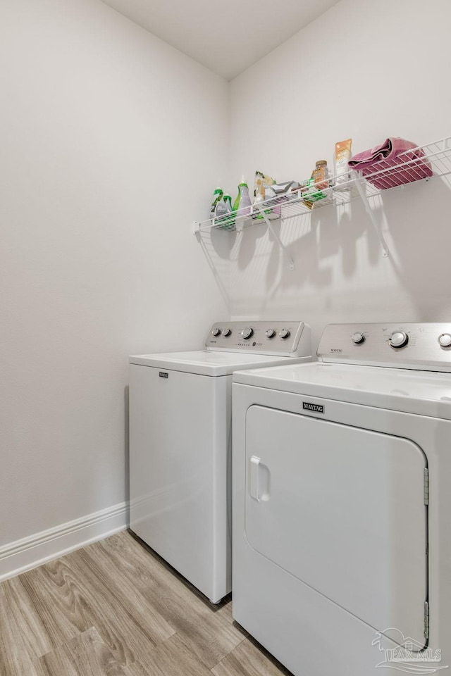 clothes washing area with light wood-type flooring and independent washer and dryer