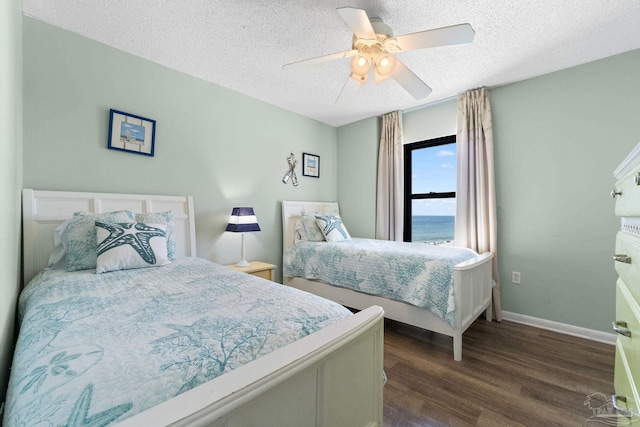 bedroom featuring a textured ceiling, ceiling fan, a water view, and dark hardwood / wood-style floors