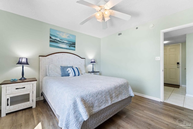 bedroom with ceiling fan, dark wood-type flooring, and a textured ceiling