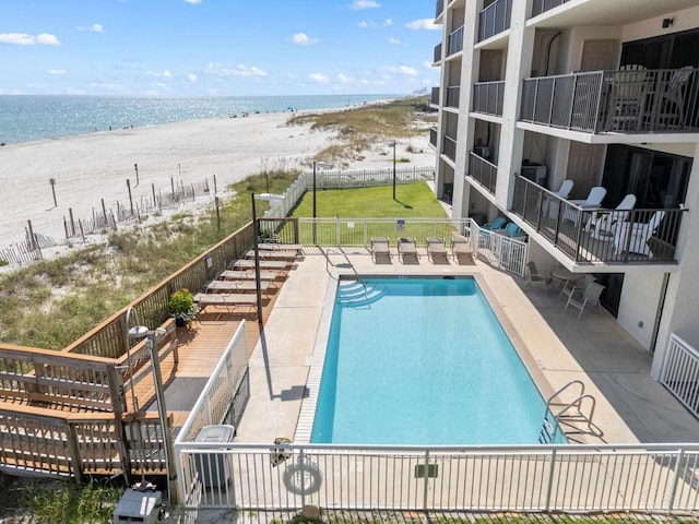 view of swimming pool with a water view, a patio, and a view of the beach