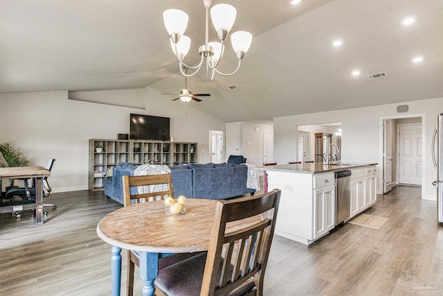 dining room featuring vaulted ceiling, ceiling fan with notable chandelier, sink, and hardwood / wood-style floors