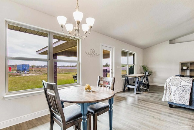 dining area with lofted ceiling, a chandelier, and wood-type flooring