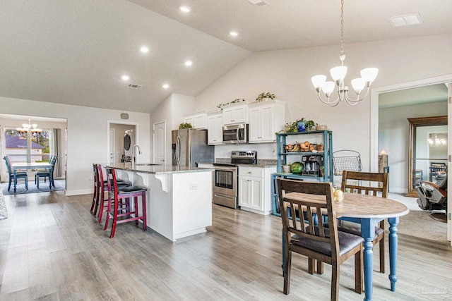 kitchen with pendant lighting, white cabinetry, a chandelier, a kitchen island with sink, and stainless steel appliances