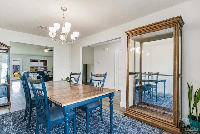 dining room featuring dark wood-type flooring and ceiling fan with notable chandelier