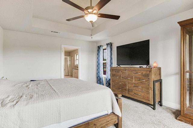carpeted bedroom with ceiling fan, connected bathroom, and a raised ceiling