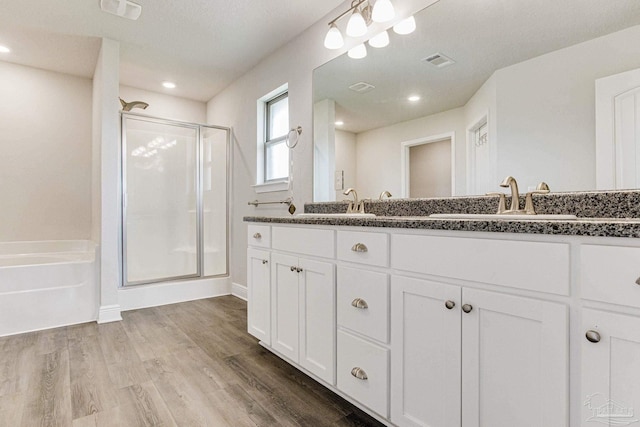 bathroom featuring hardwood / wood-style flooring, vanity, and plus walk in shower
