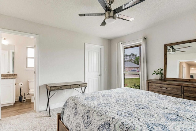 bedroom featuring multiple windows, ceiling fan, connected bathroom, and a textured ceiling