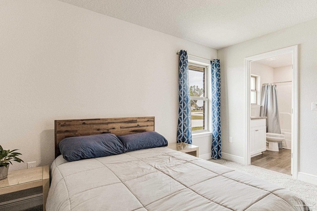bedroom with ensuite bath and a textured ceiling