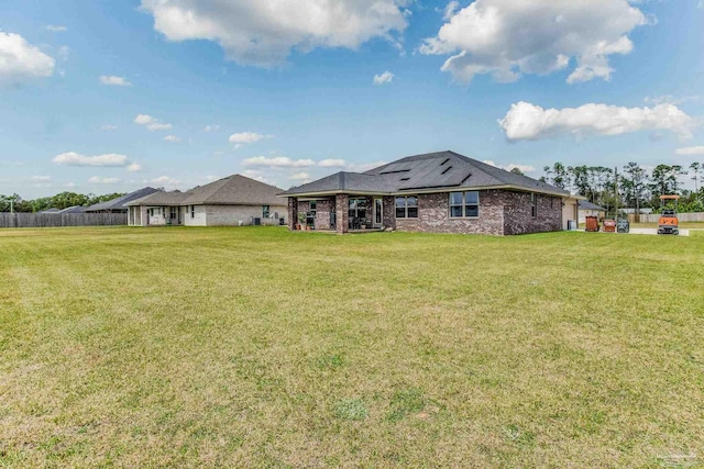 back of property featuring a lawn and solar panels