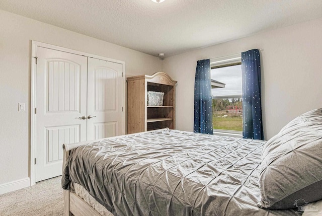 carpeted bedroom with a textured ceiling and a closet