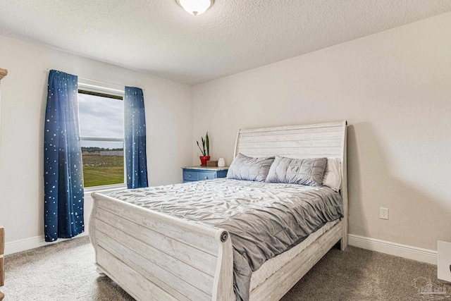 bedroom with a textured ceiling and dark carpet