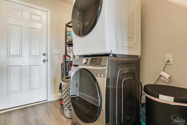 laundry area featuring hardwood / wood-style flooring and stacked washer / drying machine