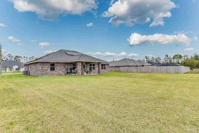 rear view of property featuring a yard and central AC