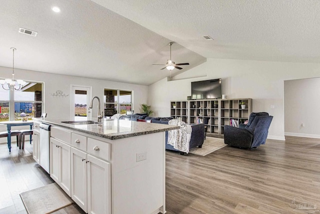 kitchen with an island with sink, white cabinets, hardwood / wood-style flooring, stainless steel dishwasher, and light stone countertops
