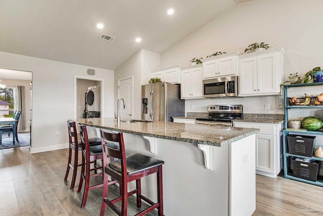 kitchen with white cabinets, appliances with stainless steel finishes, and stacked washer and clothes dryer