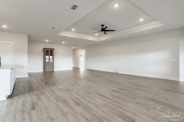 unfurnished living room featuring recessed lighting, a raised ceiling, ceiling fan, light wood-style flooring, and visible vents