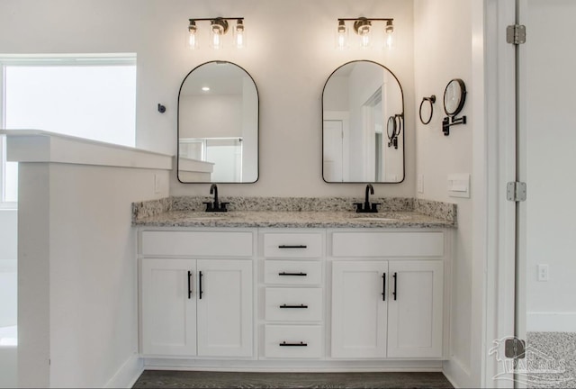 bathroom with baseboards, double vanity, and a sink