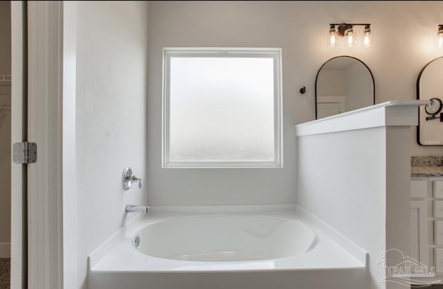 full bath featuring a garden tub and vanity