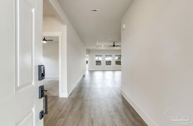 hallway featuring baseboards, visible vents, and wood finished floors