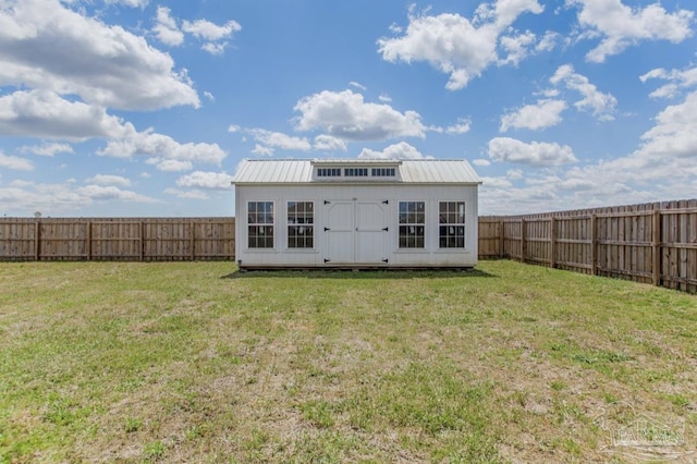 rear view of house with a fenced backyard, an outbuilding, and a yard