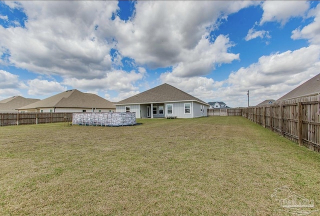 rear view of house featuring a fenced backyard and a yard