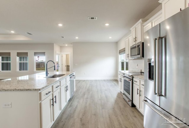 kitchen with visible vents, recessed lighting, white cabinetry, a sink, and premium appliances