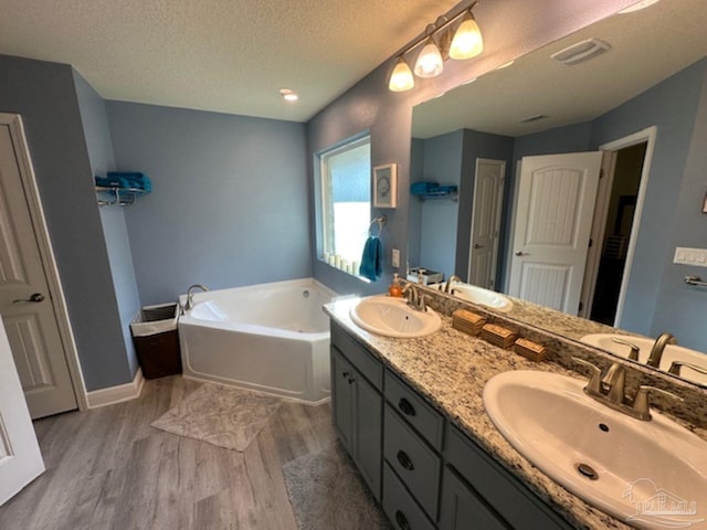 bathroom featuring vanity, a textured ceiling, hardwood / wood-style flooring, and a bathtub