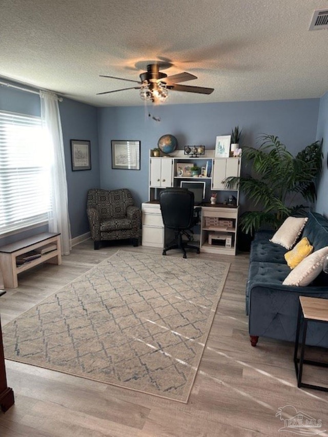 office area with a textured ceiling, light hardwood / wood-style flooring, and ceiling fan