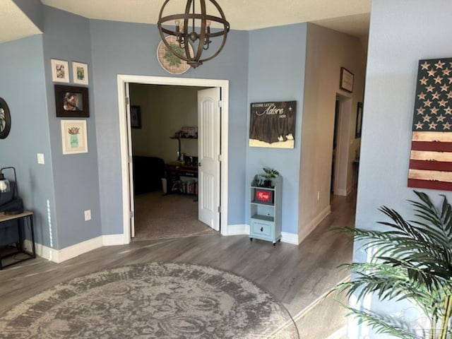 hall with dark wood-type flooring and a chandelier