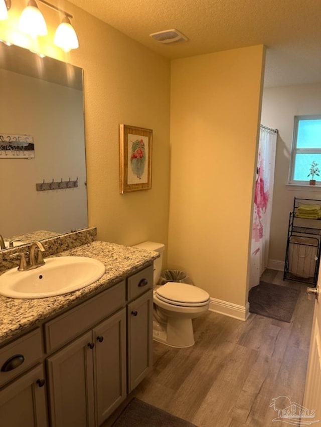 bathroom with a shower with shower curtain, vanity, a textured ceiling, hardwood / wood-style floors, and toilet