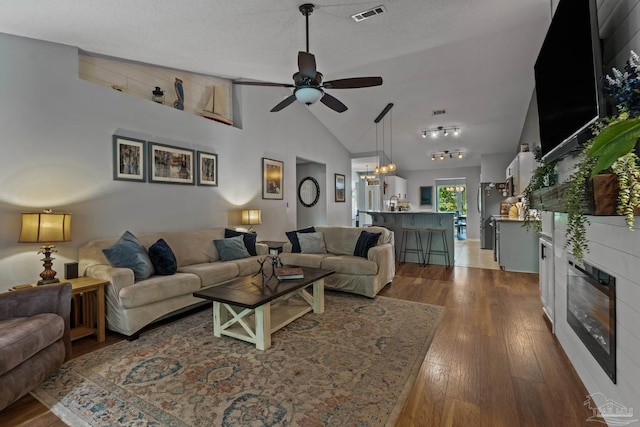 1265 Grand Ridge Cir, Gulf Breeze, FL 32563 - living room featuring a ceiling fan, wood finished floors, a glass covered fireplace, high vaulted ceiling, and a chandelier