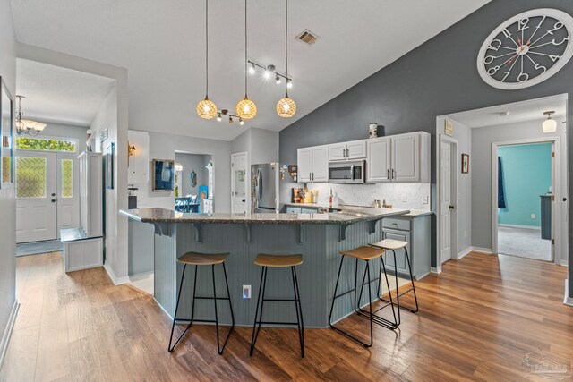 1265 Grand Ridge Cir, Gulf Breeze, FL 32563 - kitchen with lofted ceiling, light wood-style flooring, stainless steel appliances, a kitchen breakfast bar, and backsplash