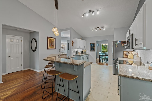 1265 Grand Ridge Cir, Gulf Breeze, FL 32563 - kitchen featuring stainless steel appliances, a breakfast bar area, white cabinets, stone counters, and lofted ceiling