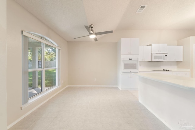 interior space featuring vaulted ceiling, white cabinetry, plenty of natural light, and white appliances